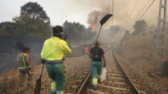 Unos voluntarios pertrechados con batefuegos caminan por la va del tren en el incendio que a finales de agosto afect al tramo bajo del ro Lor, entre A Pobra do Brolln y Quiroga 