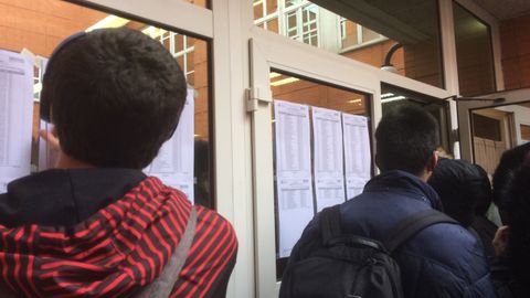 Estudiantes que se presentan al MIR en Oviedo ojeando las listas de las aulas