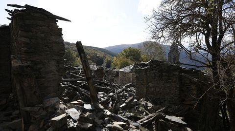 Una vivienda en ruinas en Santoalla, con la iglesia al fondo