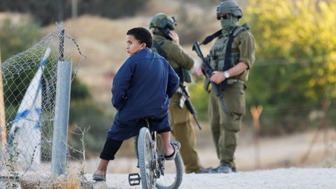 Un ni�o palestino, este martes paseando frente a los soldados isrealies en Umm al-Khair.