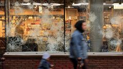 Un hombre y un nio pasan por delante de una tienda de Lille con los cristales destrozados