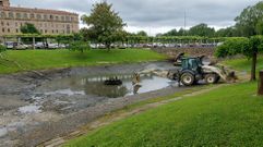 Una pala retira los fangos que arrastraron las crecidas al fondo de la laguna