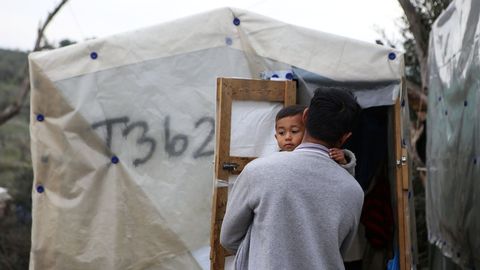 Un hombre sostiene a su hijo  en un campamento improvisado aleda�o al campo de Moria