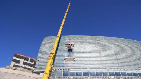 Los operarios trabajan colgados sobre la fachada-vela de la Domus, en A Coruña, para elegir el mejor método de sujeción de las losetas de pizarra