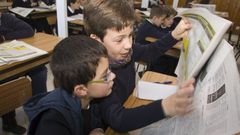 Ni�os leyendo un peri�dico en clase.