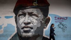 Una mujer pasea frente a un grafiti de Hugo Chávez en Caracas.