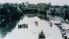 Una antigua fotografa en la que se ven el puente de hierro del Cabe (desaparecido en 1952), varias barcas navegando por el ro y un grupo de lavanderas trabajando en la orilla, a la derecha