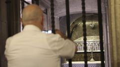 Un hombre fotograf�a, en el tabern�culo donde se rinde culto a los restos del Ap�stol, la urna de plata creada para venerar los vestigios de Santiago, obra del orfebre Jos� Losada de finales del siglo XIX que fue labrada imitando un sarc�fago rom�nico. Para bajar a la cripta es necesario dirigirse a la girola de la Catedral. En este mausoleo de espacio limitado est�n adem�s los restos de dos disc�pulos, Atanasio y Teodoro.