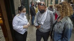 Unos clientes muestran su certificado de vacunaci�n para acceder al interior de un local en Santiago