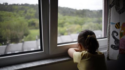 Una nia mira por la ventana durante el confinamiento